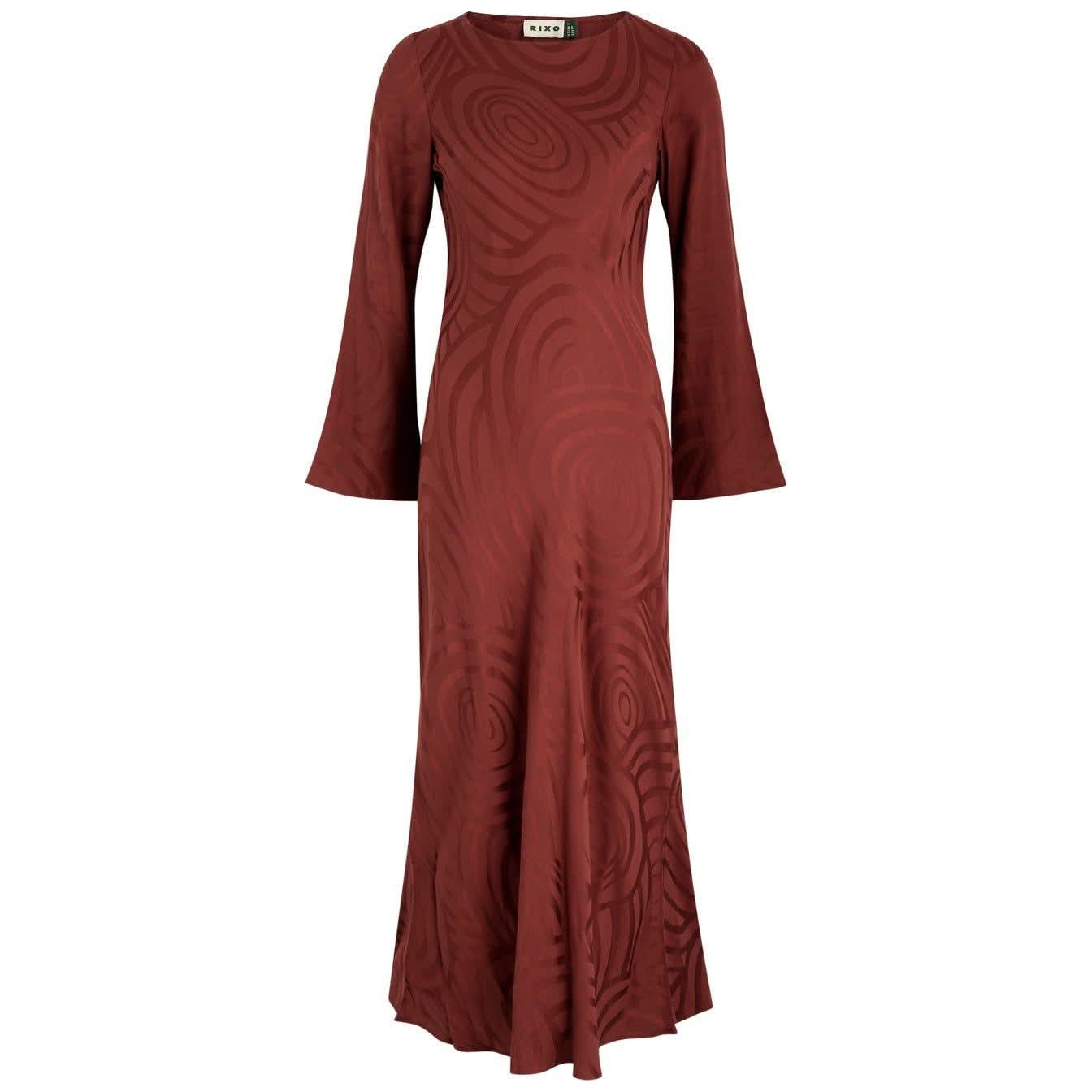 The Rixo Alondra Dress Whirlpool Jacquard Merlot is a long-sleeved, brown maxi dress featuring a fitted bodice and subtle swirl patterns throughout. Reminiscent of the elegant Alondra midi dress, this piece boasts flared sleeves and a flowing skirt crafted from luxe silk crepe de chine, creating an exquisite silhouette. A small label is stitched at the neckline for added detail.