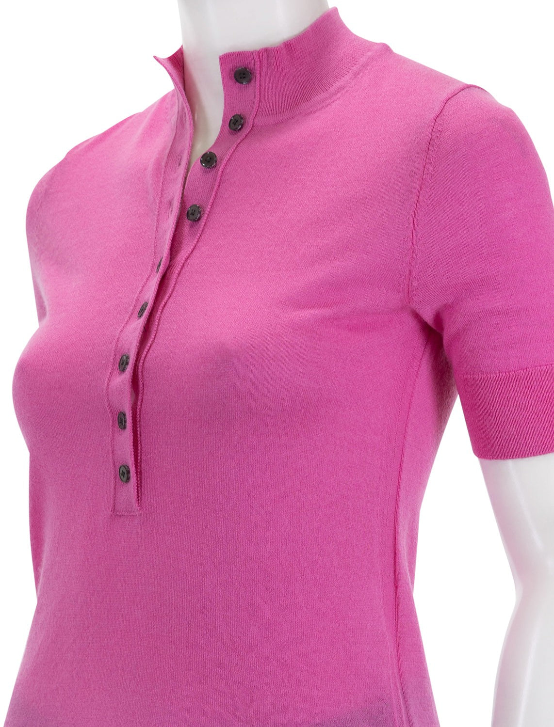 A mannequin wears the Derek Lam 10 Crosby Violette Cashmere Button Up Mockneck in Macron, a bright pink short-sleeve top with a slightly raised collar and dark buttons along the placket that extend from the collar to mid-chest, offering an elegant alternative to other cashmere tops.