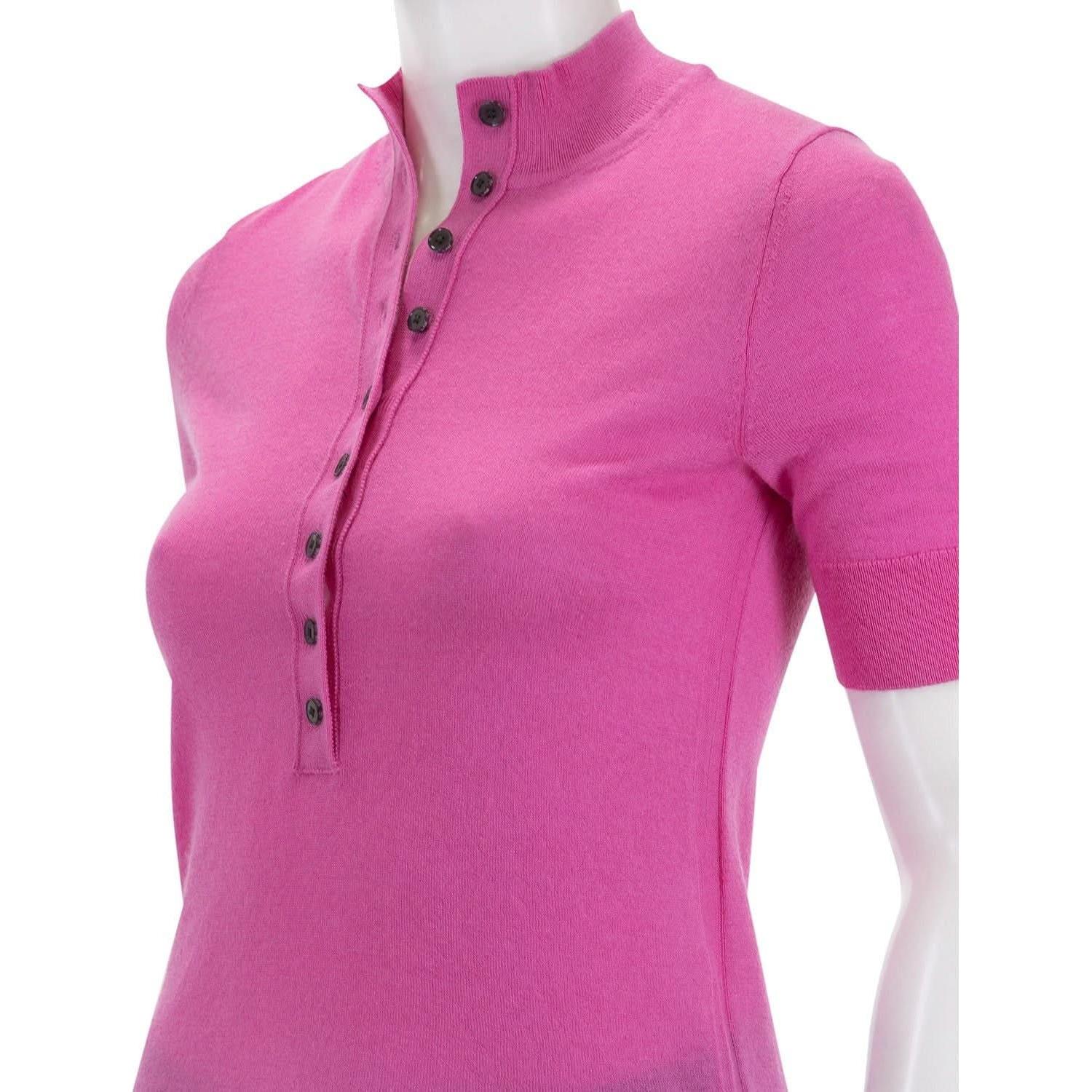 A mannequin wears the Derek Lam 10 Crosby Violette Cashmere Button Up Mockneck in Macron, a bright pink short-sleeve top with a slightly raised collar and dark buttons along the placket that extend from the collar to mid-chest, offering an elegant alternative to other cashmere tops.