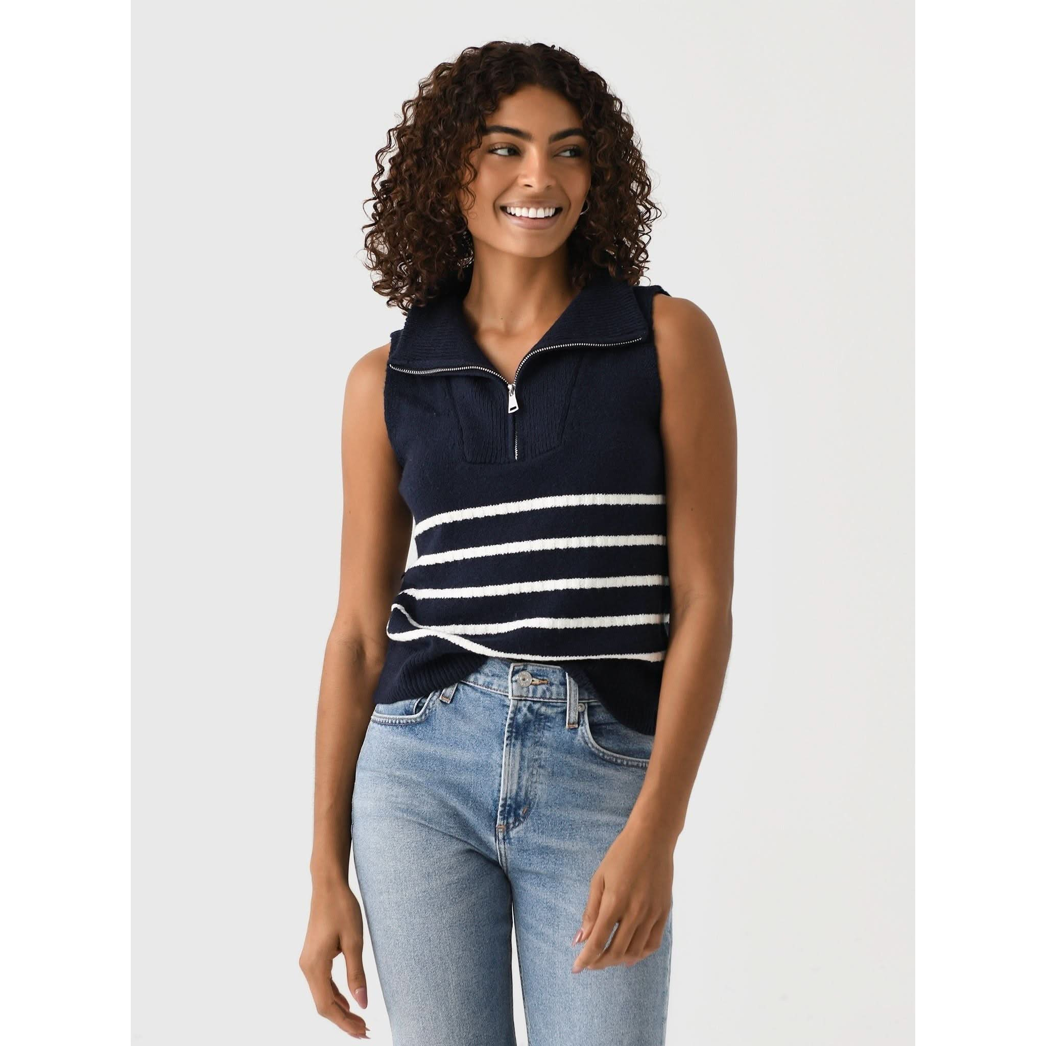 A person with curly hair is smiling and wearing the Matthew Bruch Quarter Zip Navy Knit Striped Knit Nest top, made of recycled nylon, paired with faded blue jeans. The background is plain and light-colored.