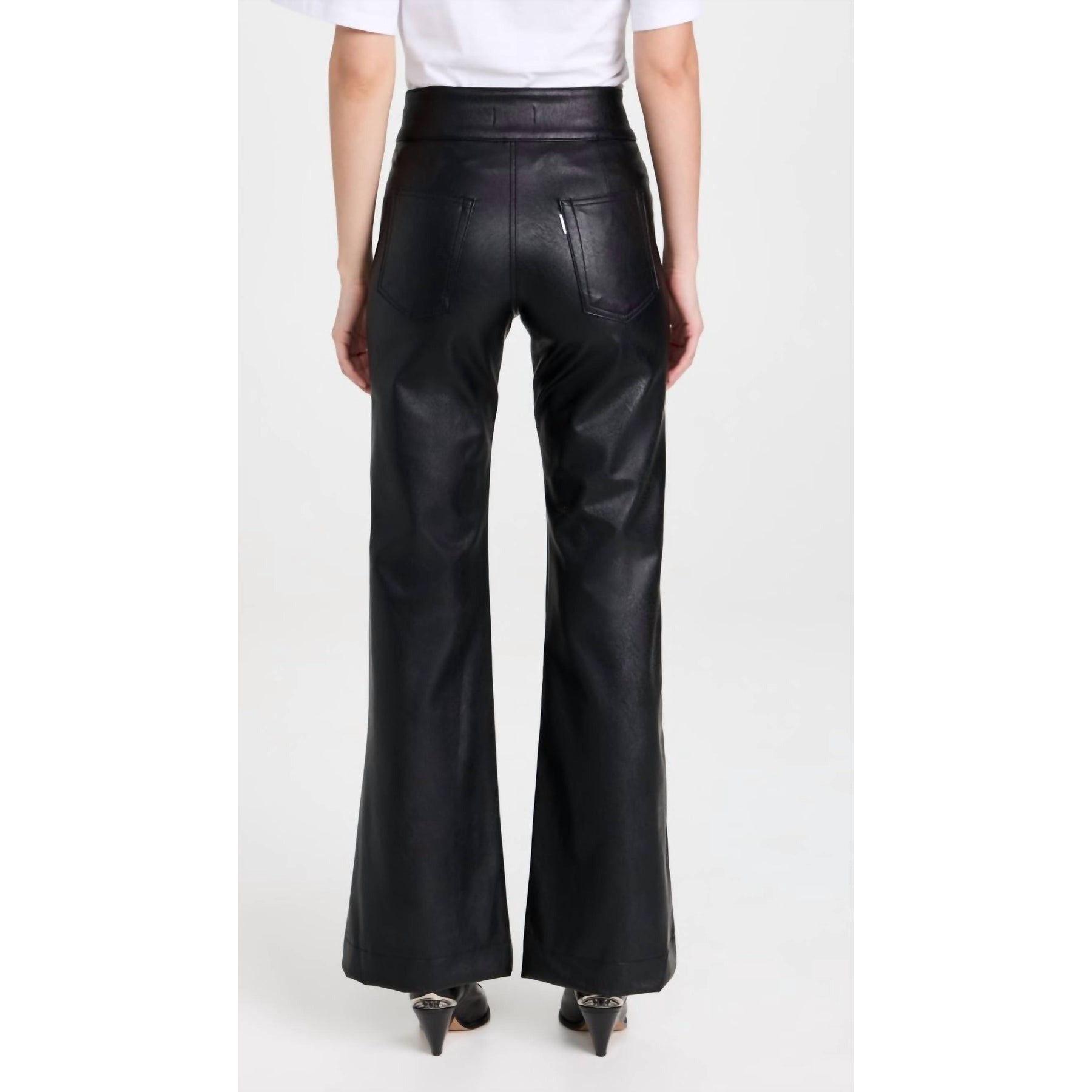 Rear view of a person wearing ASKK NY Vegan Brighton Wide Leg Black pants and black heeled shoes, standing against a plain background. The pants have pockets on the back and are reminiscent of wide-leg jeans.