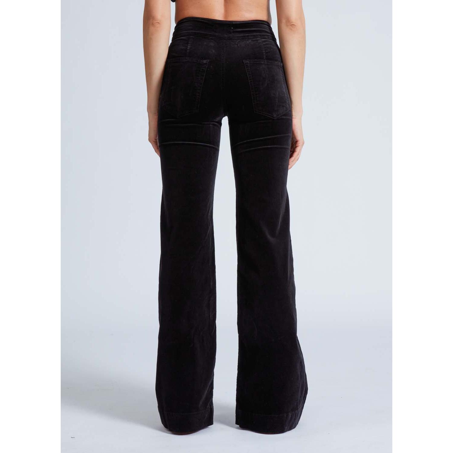 Rear view of a person wearing ASKK NY Brighton Wide Leg Black Velvet pants. These velvet pants feature visible stitching and back pockets against a plain light gray background.