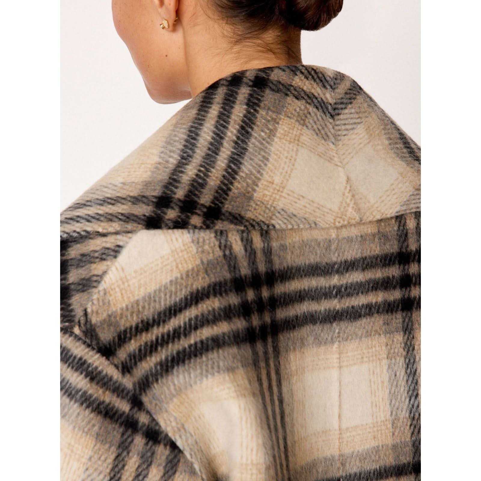 Close-up of the back of a person's head and shoulders, showing a neatly tied bun and a wool coat with a large plaid pattern in shades of beige and black. The background is plain and white, emphasizing the Brochu Walker The Finley Plaid Coat for those who appreciate timeless style.