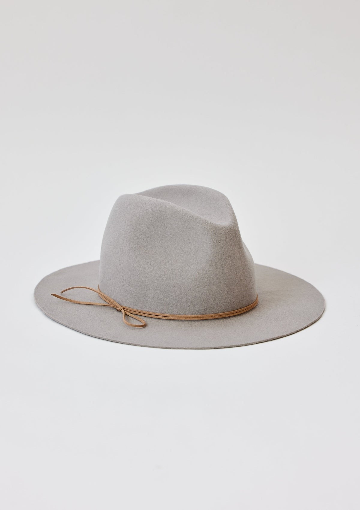 The Hat Attack Classic Amelia in light grey is a felt fedora hat with a wide brim, accented by a light brown leather band tied into a simple knot on one side. Displayed against a plain white background, it complements other headwear such as bucket hats and cotton denim styles effortlessly.