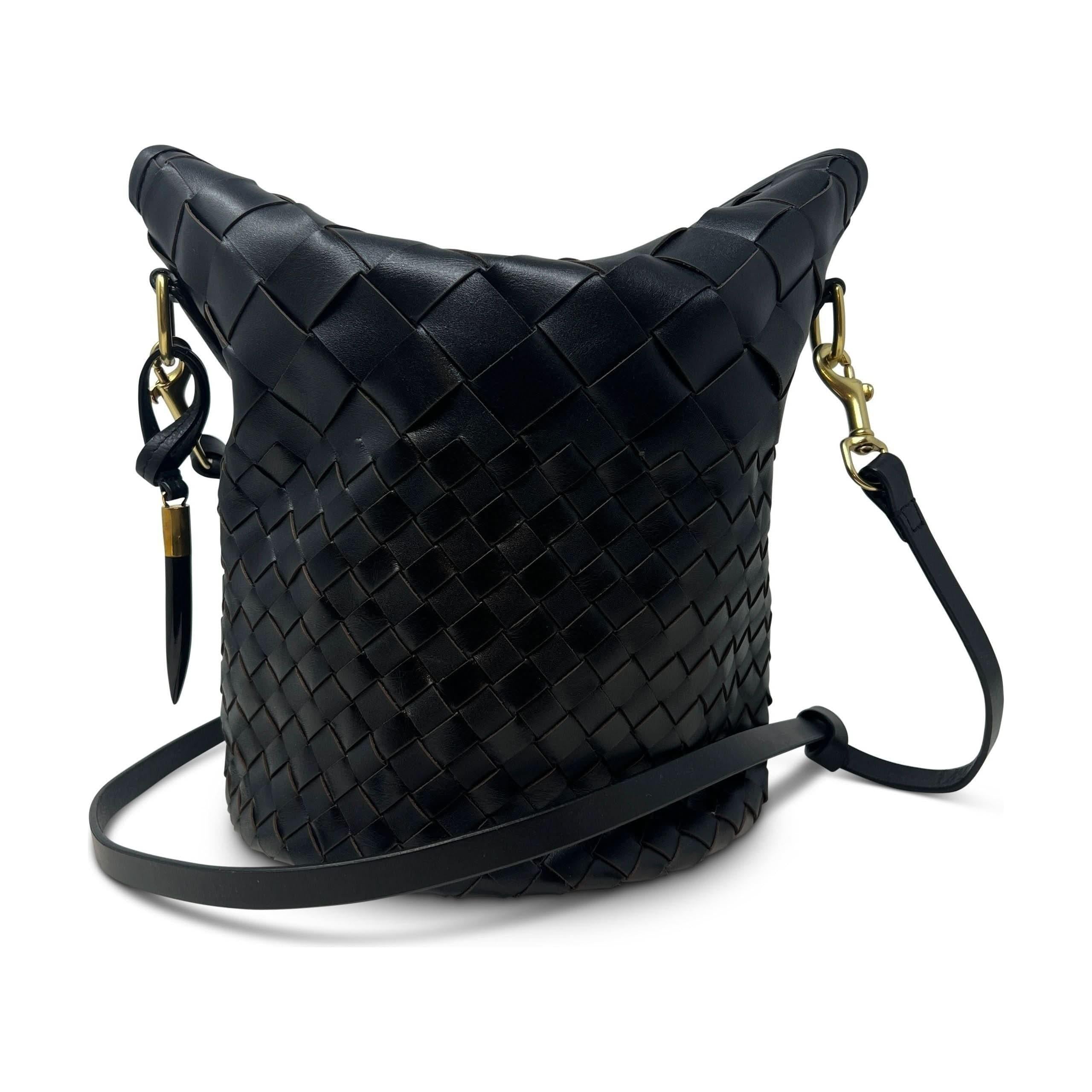 Introducing the Kempton & Co Richmond Bucket Bag - Black Threaded Weave, a stylish black woven leather bucket bag that boasts a classic cylindrical shape, gold hardware, and an adjustable crossbody strap. The intricate weaving pattern adds texture to the bag, enhancing its minimal beauty and making it both a fashionable and functional accessory from Kempton & Co.