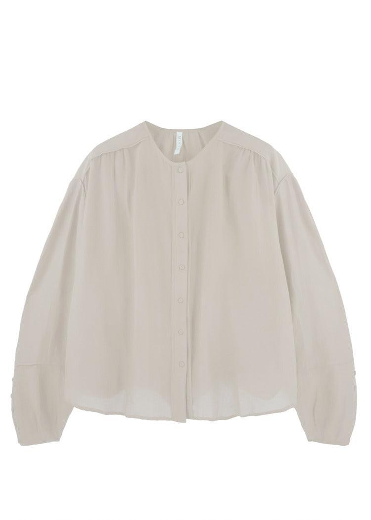 Introducing the Mirth Dakota Blouse Ivory, a light beige, long-sleeve button-up blouse from the renowned brand Mirth. This 100% silk blouse boasts an oversized fit with slightly sheer fabric and buttons adorning the front. The round neckline and cuffed sleeves at the wrists add a touch of sophistication to this exquisite piece made in India.