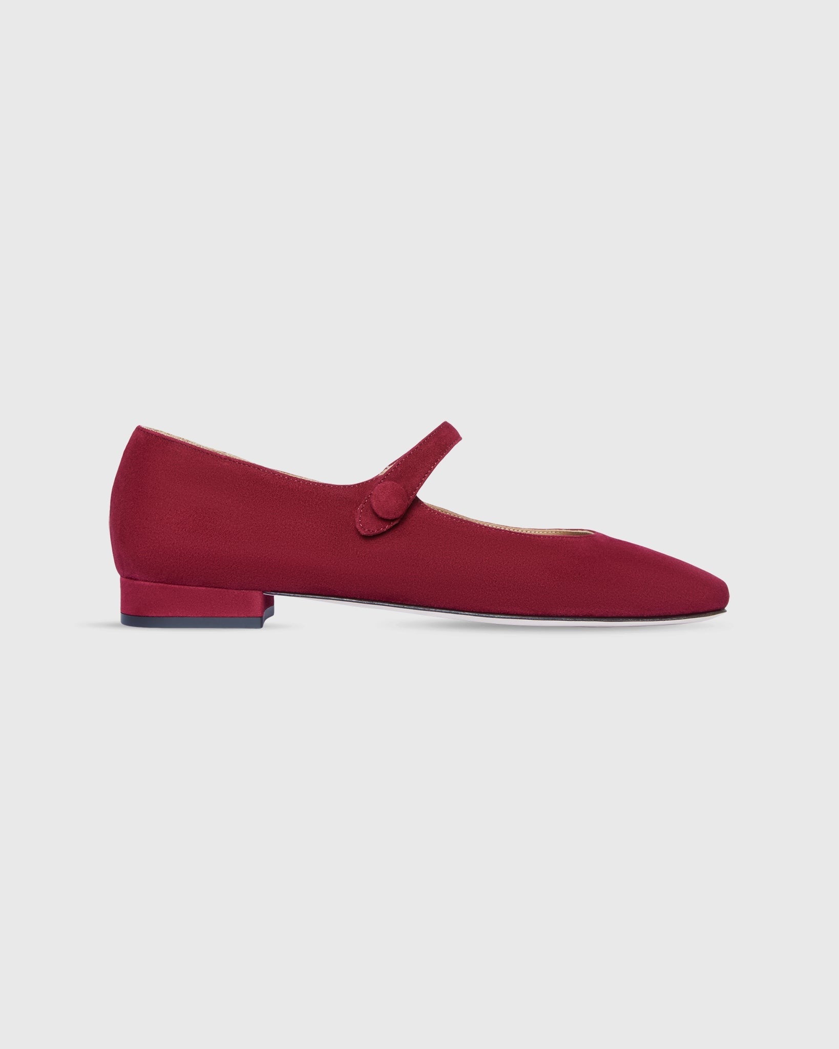 A single Ann Mashburn Square Toe Mary Jane Beet Suede flat shoe features a low block heel and a square toe. Crafted from luxurious Italian calf suede leather, this item from the Ann Mashburn brand has a strap with a button closure across the instep, exuding retro charm footwear. The shoe is set against a plain white background.