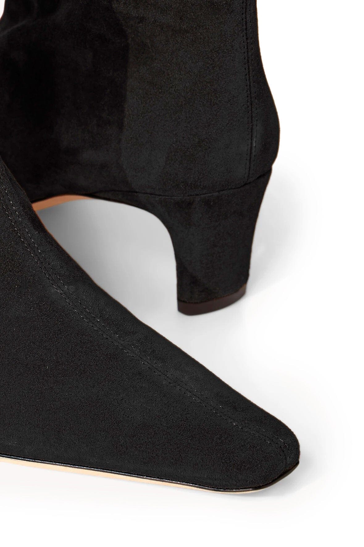 Close-up of the Staud Western Wally Ankle Boot Black by Staud, featuring black suede with a pointed toe and a mid-height blade heel. The details of the suede texture and stitching are visible.