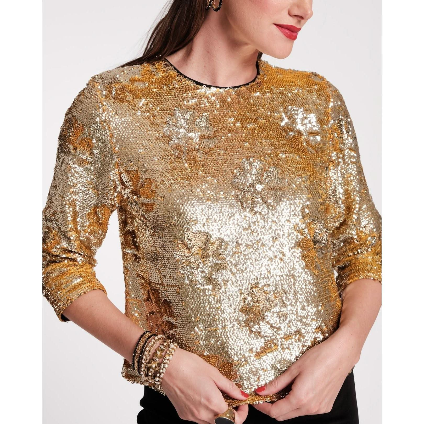 A person wearing the Frances Valentine Taylor Sequin Top in gold, embellished with exquisite floral patterns, stands out beautifully. The individual has long hair and multiple bracelets adorning their wrist, creating a stunning contrast against the plain white background.