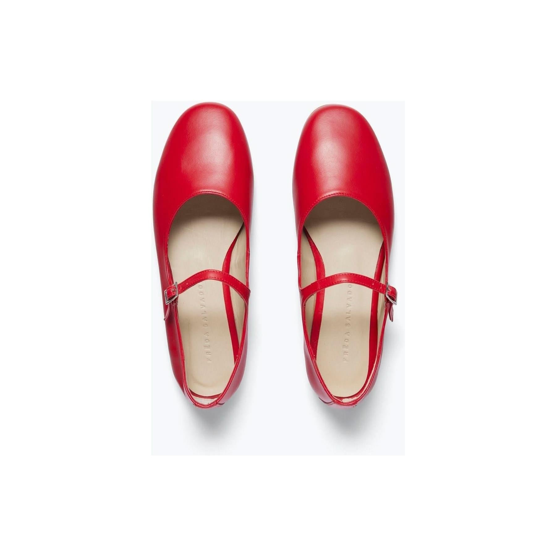 The Freda Salvador Aubrey Mary Jane Flat Red Calf shoes, made from Italian leather, are displayed in a top view. These shoes feature a round toe design and a single strap with a custom buckle. The interior lining is beige, and they are set against a plain white background.