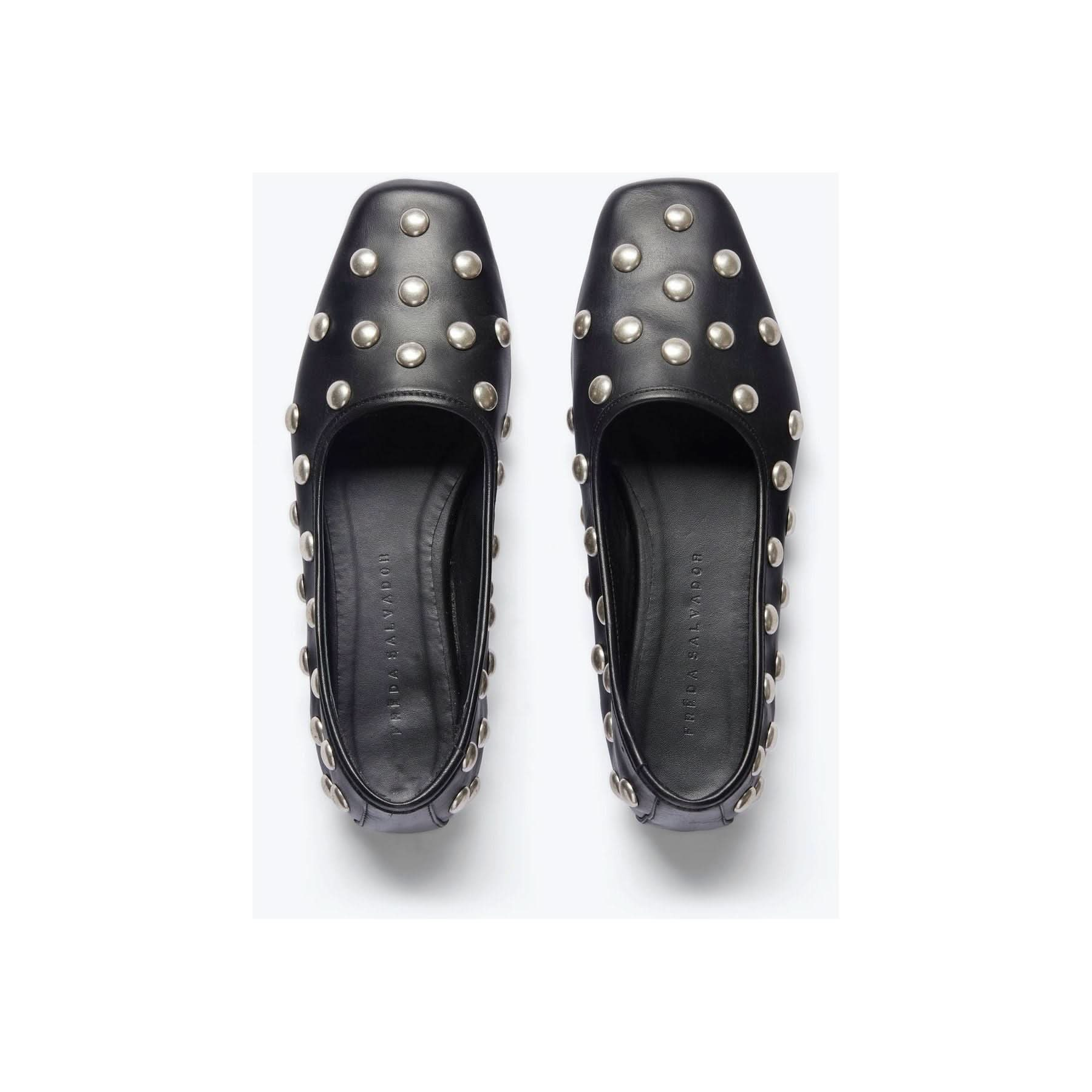 A pair of Freda Salvador's Jessie Ballet Flats, handcrafted in black, featuring a square toe and embellished with silver studs on the top and sides, set against a light gray background.